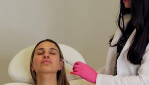 A Skin Bio injector placing dermal filler in a reclining patient’s midface during a treatment